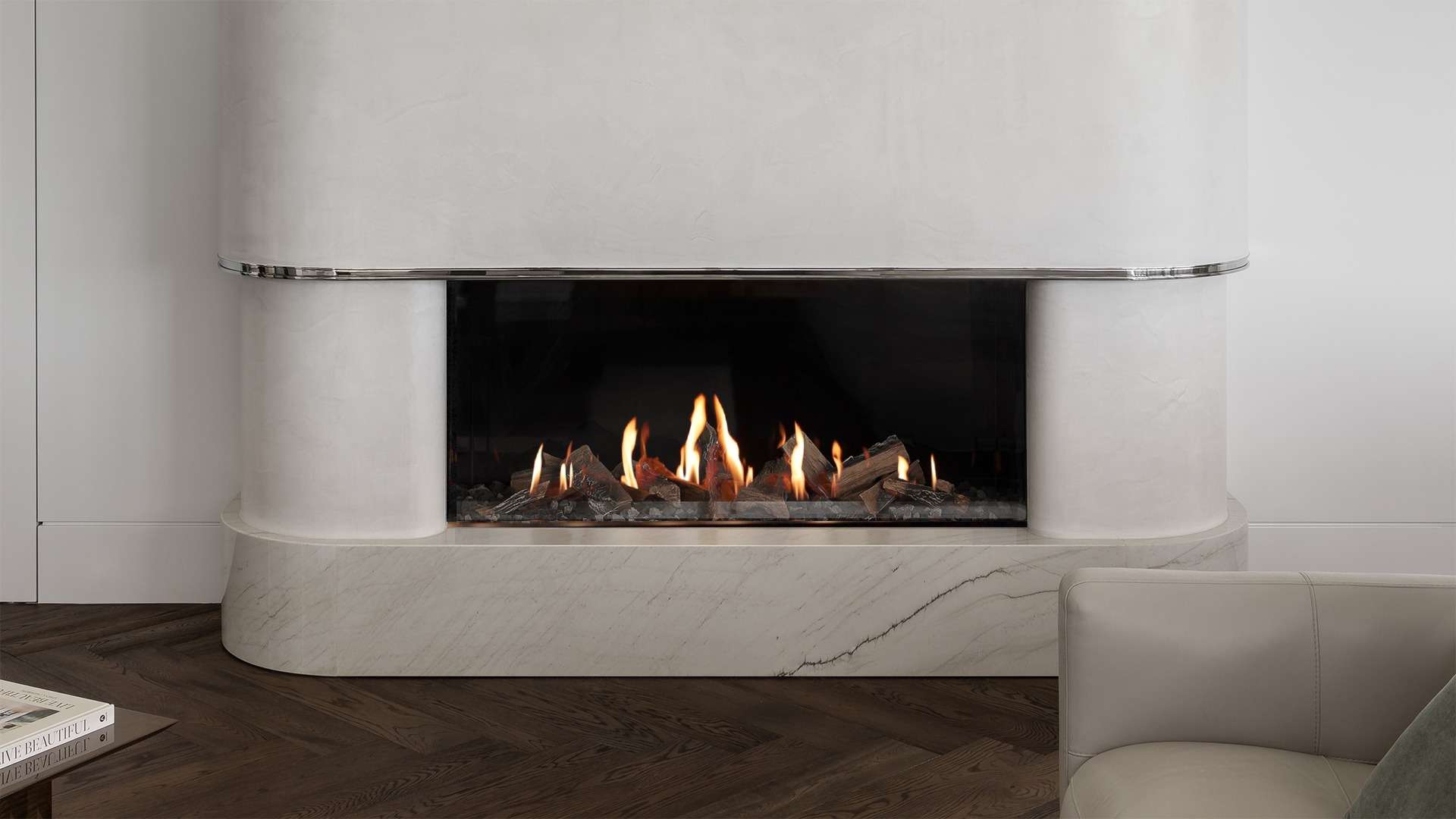 Modern gas fireplace set in a curved, plaster-finished surround with marble base and chrome detailing, framed by dark herringbone timber flooring and soft neutral-toned furniture.